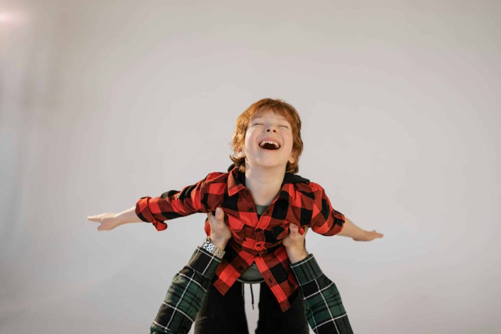 The boy is being lifted by the parent and looks joyful